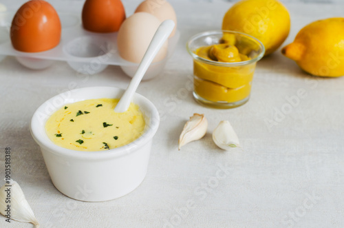 Tableau sur toile Fragrant garlic Aioli sauce in a white bowl with ingredients on a light gray bac