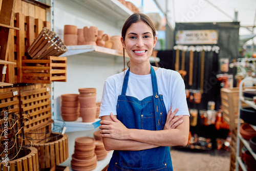 Bild auf Leinwand Smiling woman wearing an apron in a garden center, representing small business o