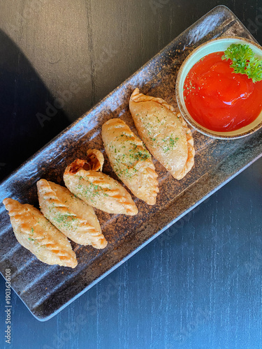 Fried Indonesian Pastel (Empanada) with Chili Sauce on a Modern Ceramic Plate