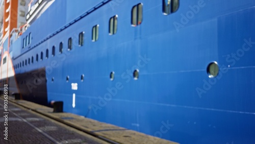 Foto Blue cruise ship hull with round portholes and painted metal panels, defocused and softly blurred outdoor; background copyspace calm