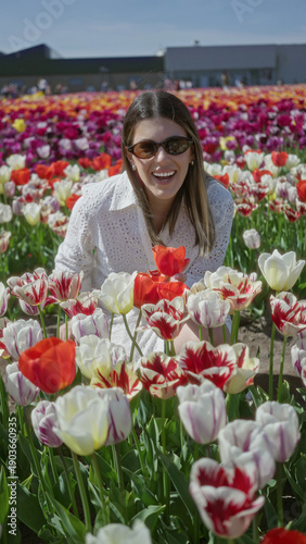 Foto Woman enjoying a stroll through vibrant tulip fields in lisse, netherlands, wearing a white dress and sunglasses, surrounded by colorful flowers under a clear sky