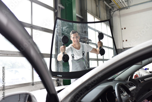 Photos mechanic in a garage replaces defective windshield of a car