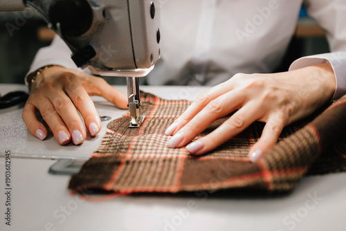 Photos Designer works on fabric with a sewing machine, shaping apparel and custom garments