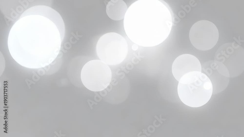 Soft focus bright white bokeh circles and tiny specks on a blurred grey background