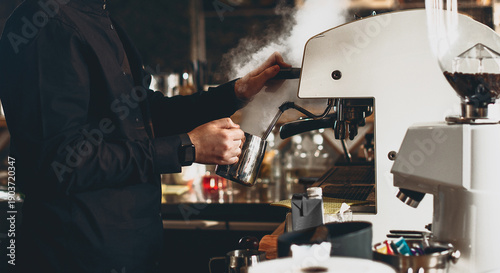Barista hands steaming milk near coffee machine close up