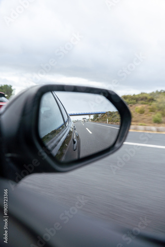 A car is driving down a road with a blue sky in the background