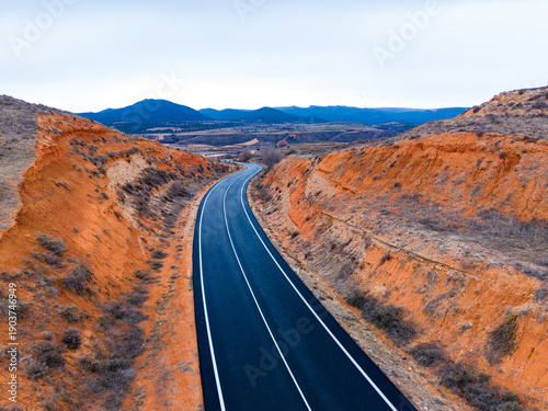 Curved road through rocky landscape in a remote area during the daytime showing mountains in the distance