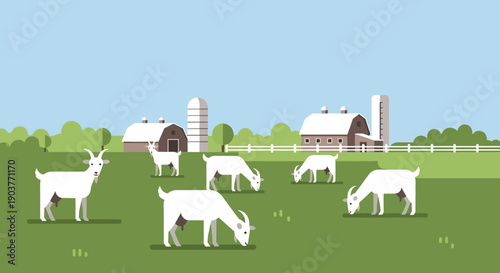 White goats graze peacefully on a vibrant green pasture with traditional farm buildings and silos under a clear blue sky.