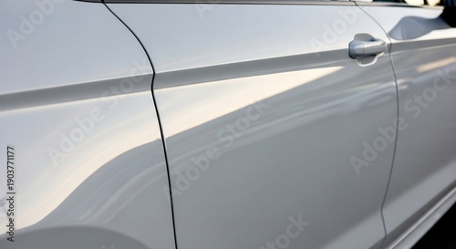 Closeup of a white car door with a handle and a sleek design capturing the light.