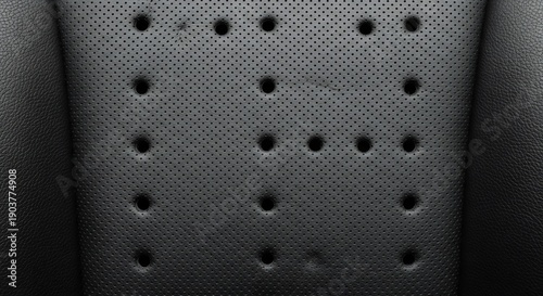 Closeup view of a black perforated leather car seat with multiple holes.