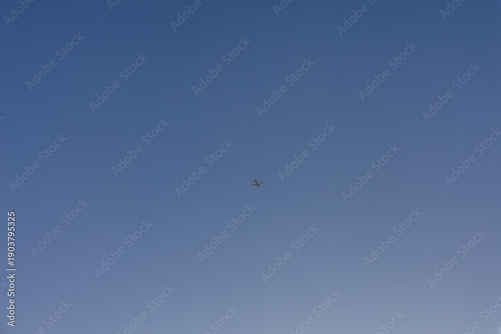 Fototapeta premium Airplane flying high in clear blue sky, copy space