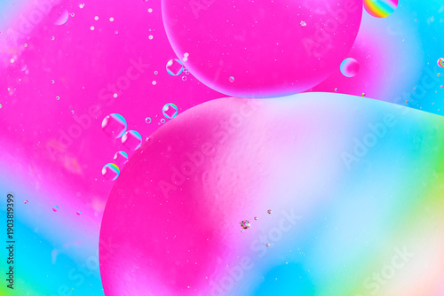 Large oil bubble floating over pink and blue gradient liquid surface.