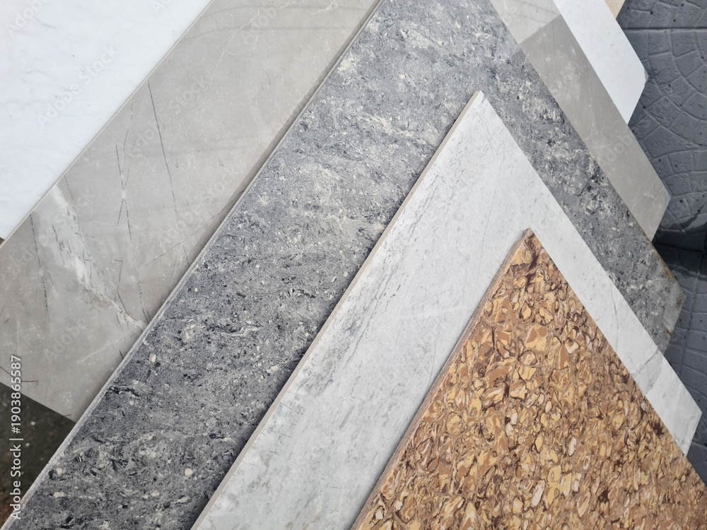 Fototapeta premium Various textured surfaces including gray marble, light marble, and cork. The materials are arranged in a layered fashion, showcasing their unique patterns and colors.