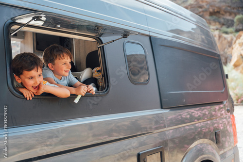 Happy children looking out camper van window