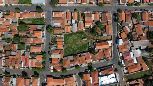 Cuadro en lienzo Aerial view of a residential neighborhood with red tile roof houses and an empty urban lot in the center of a small Brazilian city