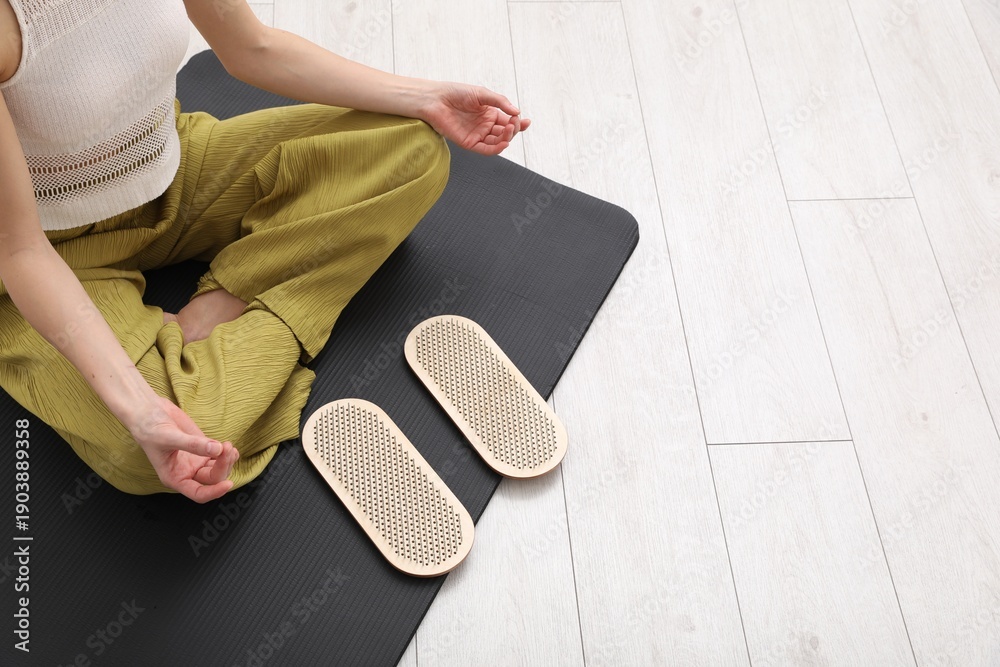 Fototapeta premium Young woman with sadhu boards meditating on yoga mat at home, closeup. Space for text