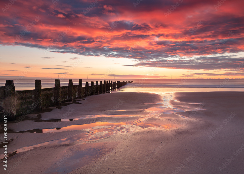 Fototapeta premium Sunrise and colourful morning light on Blyth Beach on the coast of Northumberland, England, UK.