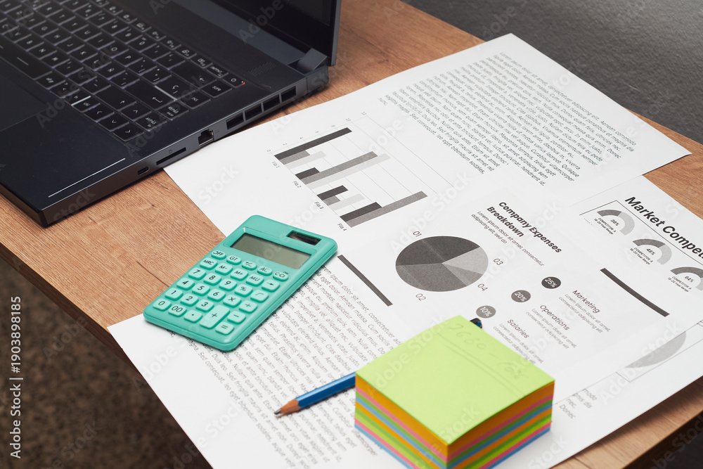 Obraz premium Office workspace with laptop, calculator and market analysis documents