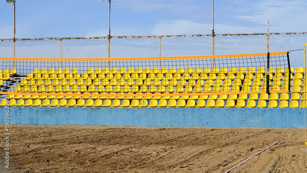 Fototapeta premium Yellow seating area with volleyball net at sandy beach sports venue