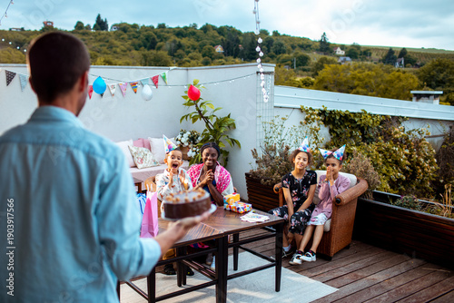 Quadro em tela Father bringing birthday cake to kids on rooftop patio