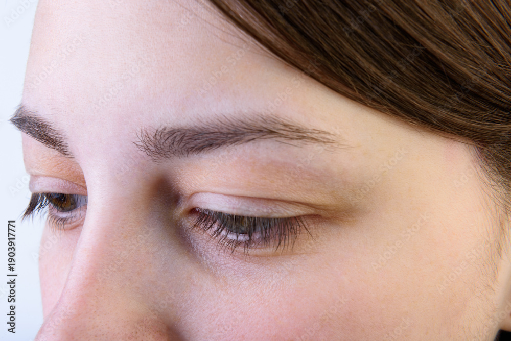 Obraz premium Young girl after treatment, eyebrow correction on gray background.