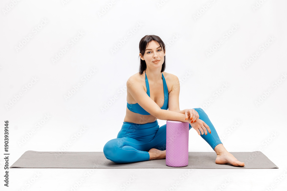 Fototapeta premium Woman training on fitness mat with foam roller. Fitness, wellness and active lifestyle concept.