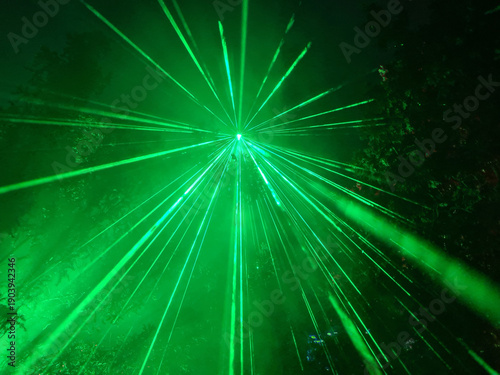 green laser light in a forest with many beams in the dark sky 