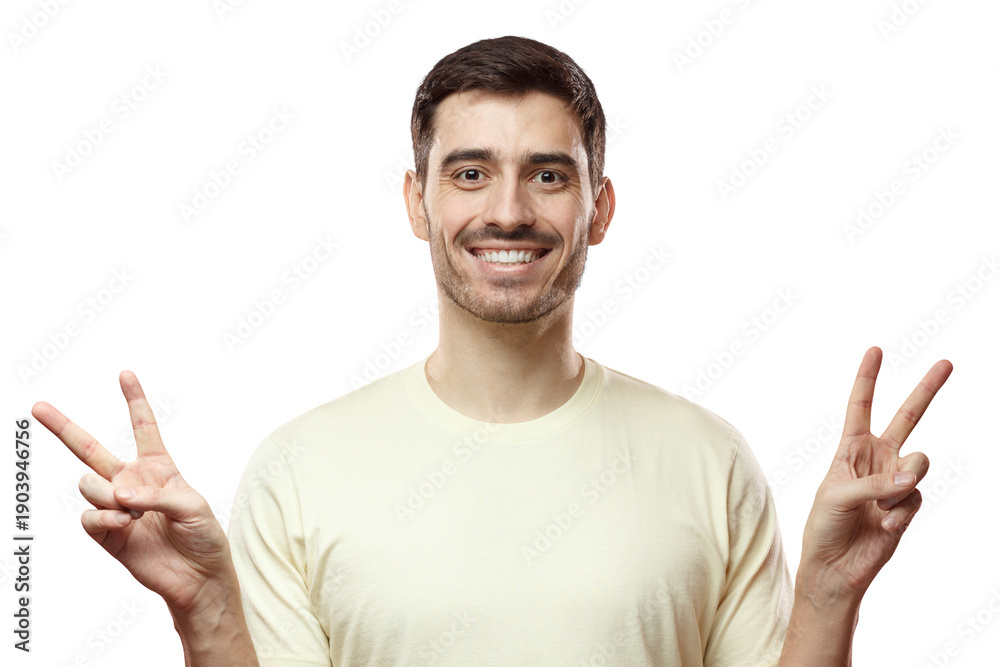 Fototapeta premium Closeup photo of young positive European man in beige T-shirt isolated on pink background feeling peaceful and comfortable, smiling and showing V sign with fingers, enjoying relaxed atmosphere