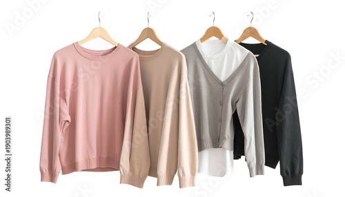 Four neutral-colored sweaters and a cardigan hang on wooden hangers against a white backdrop