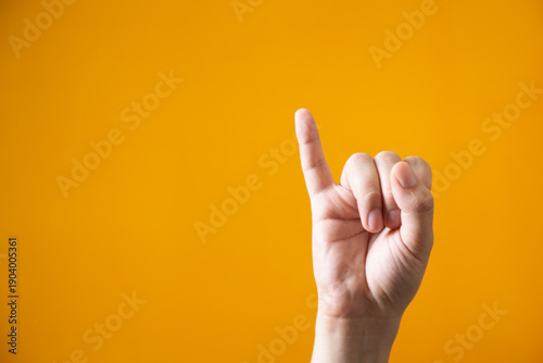 Photos Close up of pinky finger raised on bright yellow background signifying a concept