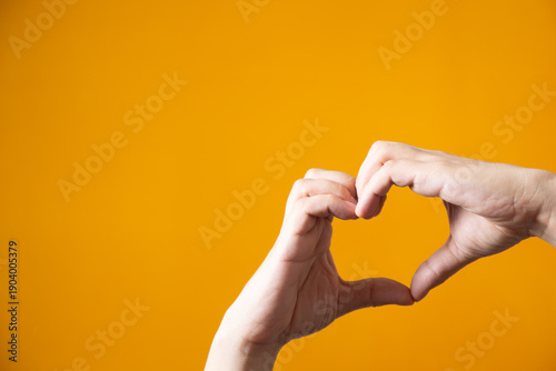 Fotografía Two hands forming a heart shape on yellow background illustrating a concept of r