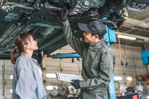 Φωτογραφία 自動車の下回りで整備士,メカニックから説明を受ける女性客