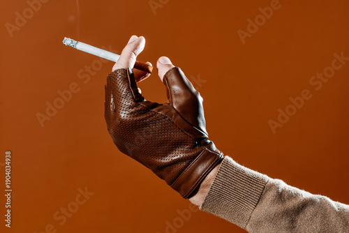 a man lifting a cigarette wearing a brown leather glove