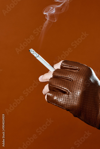 smoke rising from a cigarette held by a man wearing a leather glove