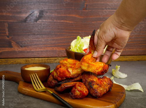 Food: Grilled marinated chicken wings on a wooden cutting board, black background