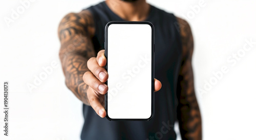 Man with Tattoos Holding Up a Smartphone with a Blank White Screen.