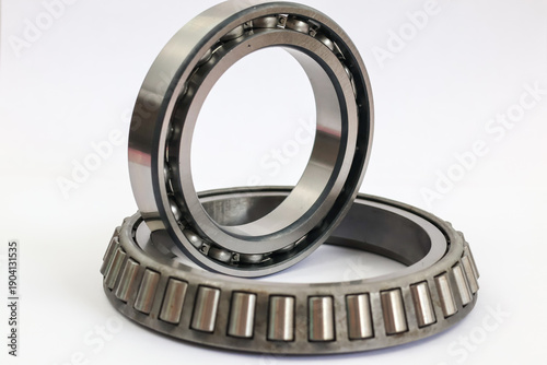 Comparison of industrial ball bearing and tapered roller bearing stacked on white background professional mechanical parts for automotive and machinery repair.