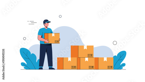 Delivery man in a blue uniform carrying a cardboard box while standing next to a stack of packages on the ground.