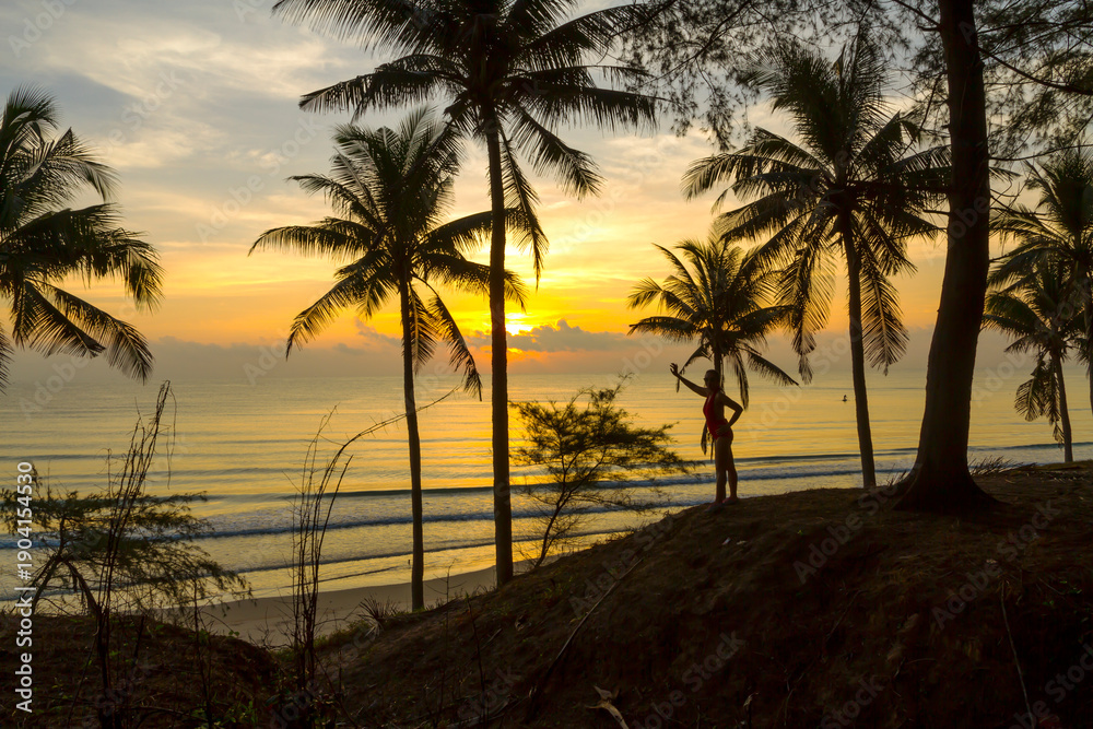 Obraz premium Sunrise with silhouette woman and coconut