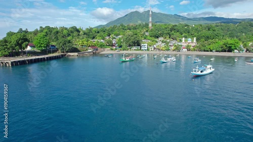 Wallpaper Mural Cinematic drone footage of a peaceful coastal village with colorful fishing boats anchored in a blue bay, surrounded by lush green hills. Torontodigital.ca