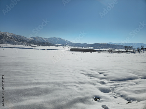 Foto Vast snowy landscape with distant mountains under a clear blue sky, showcasing the peaceful beauty and untouched purity of a bright winter day