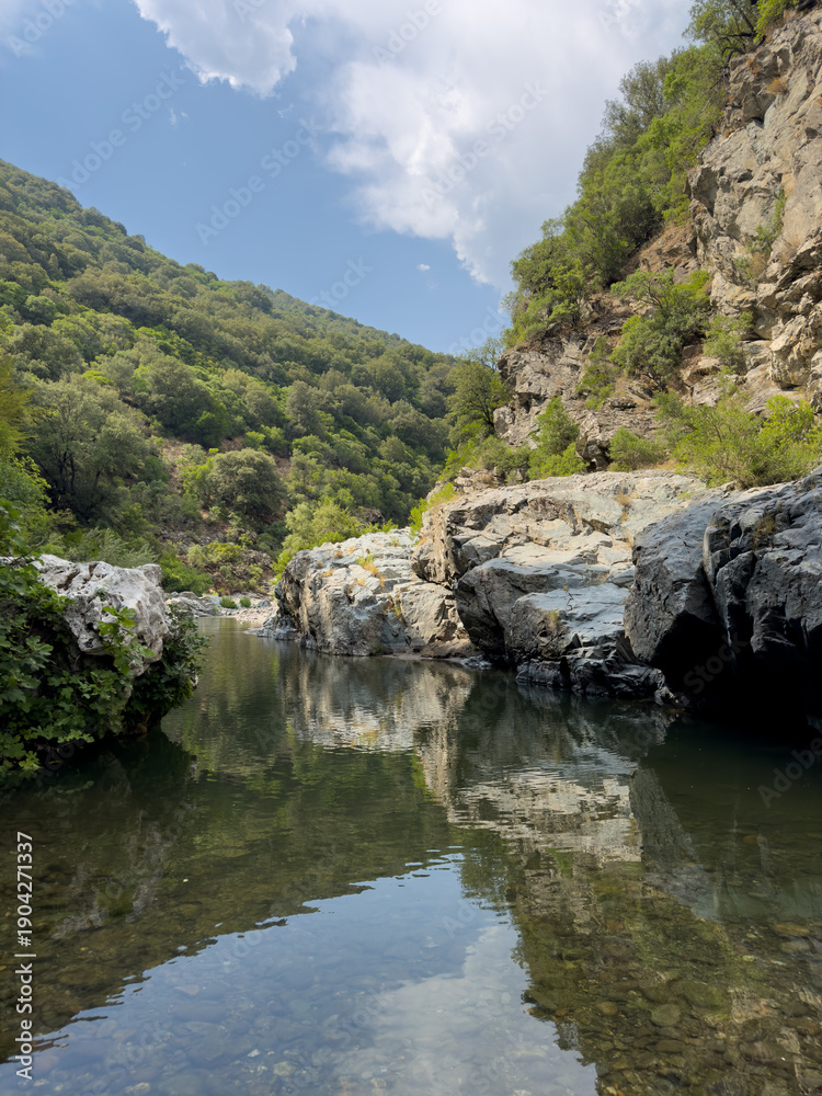 Fototapeta premium Scenic view of the transparent natural pools and rocky riverbed of Sa Stidiosa, surrounded by green Mediterranean hills in Sardinia, Italy.