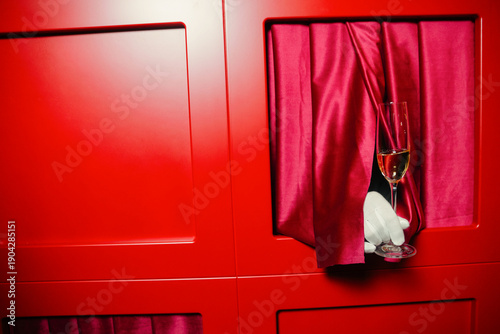 hand in fishnet gloves with champagne glass on red glam background
