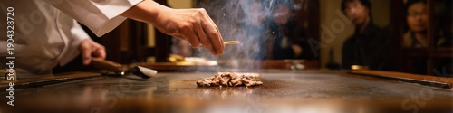 Chef skillfully grilling wagyu beef slices on a teppanyaki griddle for admiring customers in a gourmet restaurant