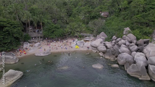 Beach on Koh Tao with people hanging out, rocks and cool sea. original file