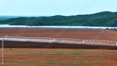 Aerial footage of a center pivot irrigation system operating across an agricultural field. The irrigation structure distributes water evenly.