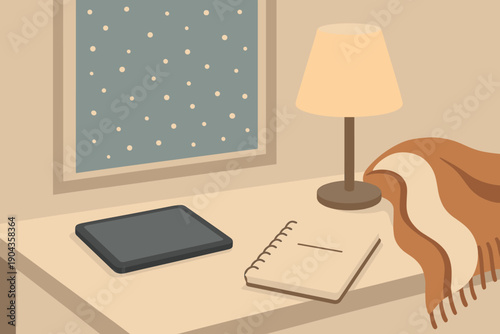 Cozy workspace with a tablet, notebook, and lamp by a window during snowy weather