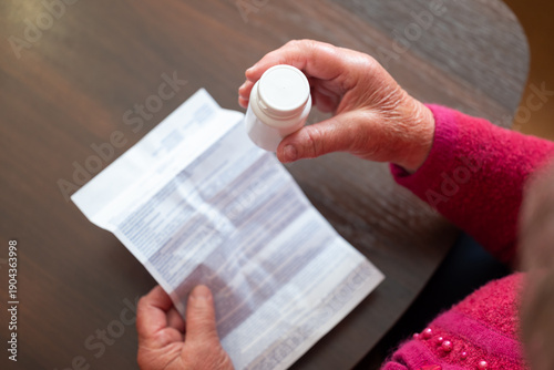 Pensioner reading the instruction leaflet for medication. Retired woman's hands holding a blister pack of pills and carefully reading the paper instruction leaflet, health care, the treatment routine