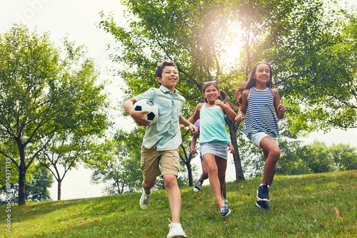 Foto Friends, children and happy for running at park with football, outdoor and bonding on summer vacation
