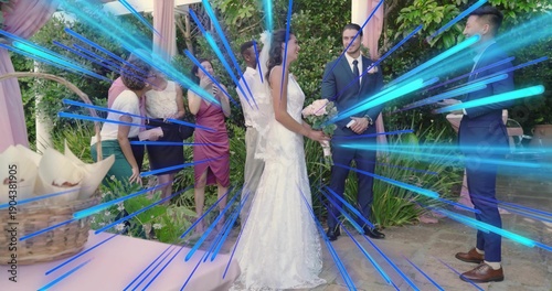 Holding bouquet, bride in white-lace gown standing at garden with dark-suit men, arch, blue overlay
